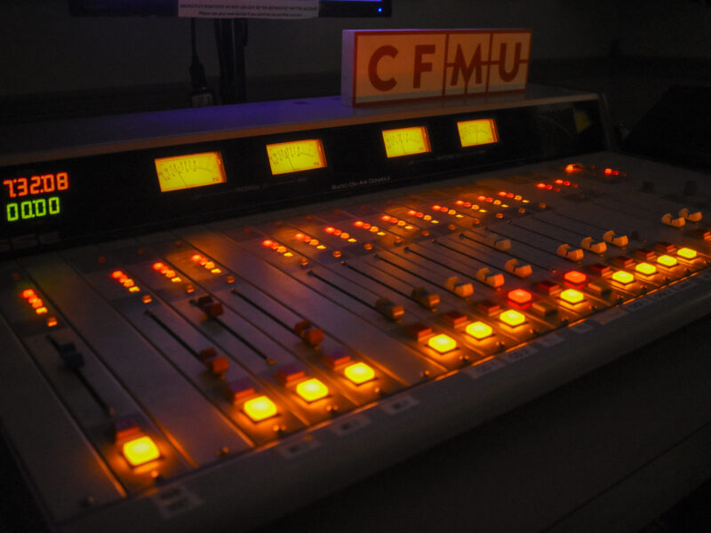 A radio station control board showing the dials glowing in a dark room