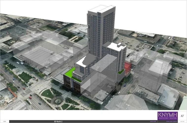 A 3D digital architectural model overlaid onto an aerial photograph of downtown Hamilton looking northeast over Gore Park. The rendering shows a massive, dark tower complex rising next to the historical buildings on King Street East, featuring a green rooftop podium space. Surrounding city blocks are represented by transparent grey massing blocks.
